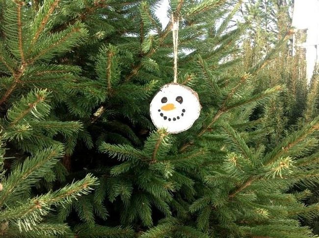 Wooden Snowmen Among Pine Branches